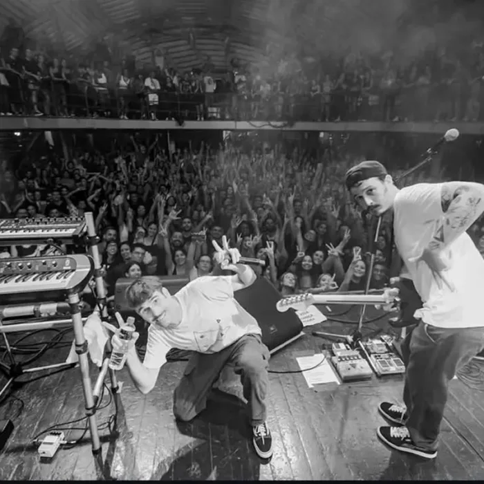 Fotografia em preto e branco com ponto de vista de trás do palco com grupo Braza em apresentação no Circo Voador.