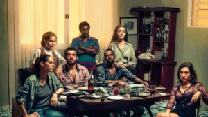 Personagens da série "Impuros", dos Disney+, reunidos em torno de mesa. Caracterização e ambientação de casa no estilo dos anos 90.