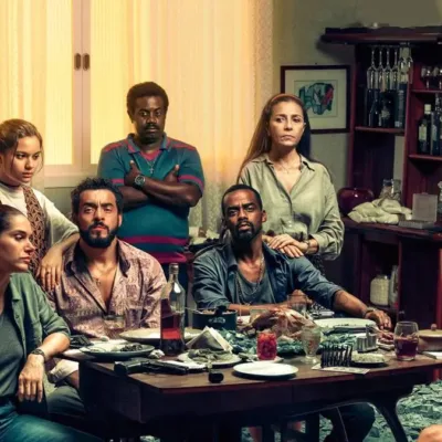 Personagens da série "Impuros", dos Disney+, reunidos em torno de mesa. Caracterização e ambientação de casa no estilo dos anos 90.