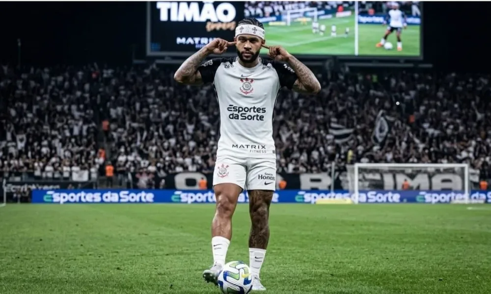 Memphis Depay com o uniforme do Corinthians, dedos levados ao ouvido, durante partida. Imagem gerada por IA.