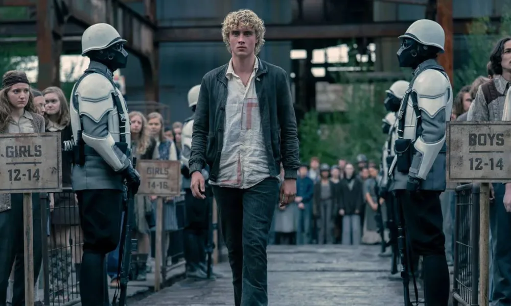 Joseph Zada como Haymitch Abernathy, protagonista do segundo filme spin-off de Jogos Vorazes: "Amanhecer na Colheita". Jovem anda entre guardas e adolescentes são separados por fila por idade na seleção de tributos.