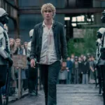 Joseph Zada como Haymitch Abernathy, protagonista do segundo filme spin-off de Jogos Vorazes: "Amanhecer na Colheita". Jovem anda entre guardas e adolescentes são separados por fila por idade na seleção de tributos.