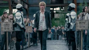 Joseph Zada como Haymitch Abernathy, protagonista do segundo filme spin-off de Jogos Vorazes: "Amanhecer na Colheita". Jovem anda entre guardas e adolescentes são separados por fila por idade na seleção de tributos.