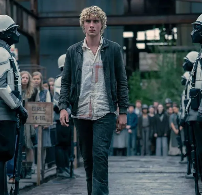 Joseph Zada como Haymitch Abernathy, protagonista do segundo filme spin-off de Jogos Vorazes: "Amanhecer na Colheita". Jovem anda entre guardas e adolescentes são separados por fila por idade na seleção de tributos.