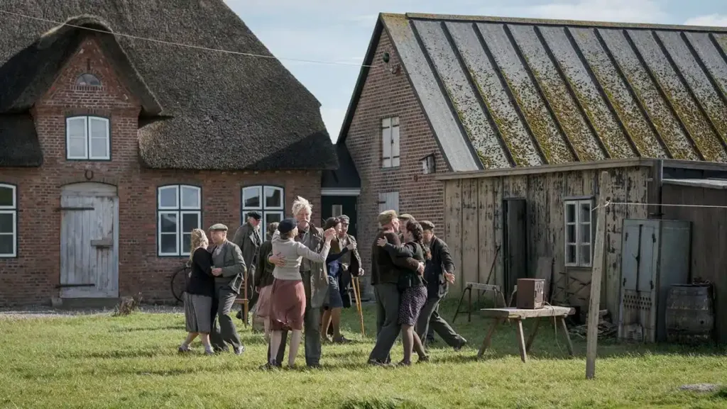 Cena de dança de comunidade de dia ao ar livre no filme "Uma Infância Alemã".