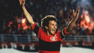 Crop do pôster do filme documentário "Zico: Samurai do Quintino", da Globo Filmes. Jogador está em partida comemorando gol com braços erguidos.