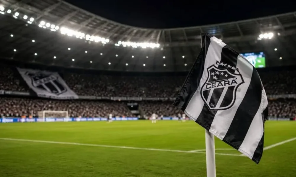 Bandeira do Ceará em riste em campo de futebol de noite durante partida, em destaque. Imagem gerada por IA.