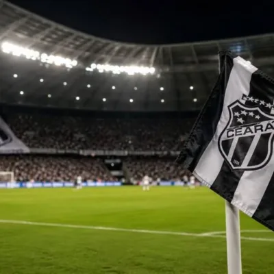 Bandeira do Ceará em riste em campo de futebol de noite durante partida, em destaque. Imagem gerada por IA.