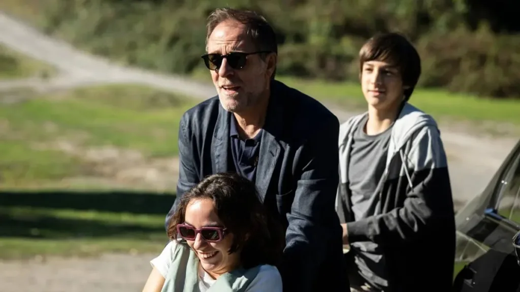 Still do filme "Cinco Segundos" (2025) com Adriano Sereni (Valerio Mastandrea) levando uma estudante na cadeira de rodas.