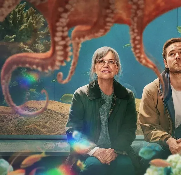 Imagem de divulgação, horizontal, do filme "Criaturas Extraordinariamente Brilhantes". Protagonistas obsevam polvo em aquário com fascínio.