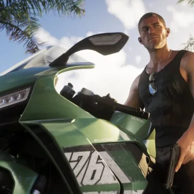 A imagem mostra o protagonista do jogo Grand Theft Auto V, Jason, em uma motocicleta Principe, segurando um revólver com a mão esquerda, olhando à direita. Imagem em contra plongée.