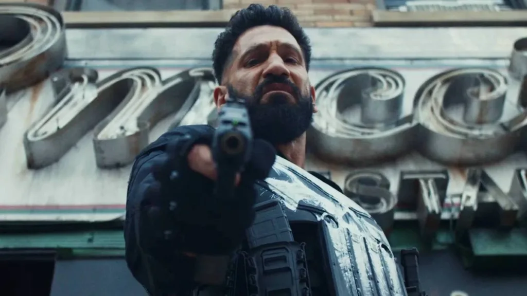 O Justiceiro: Uma Última Morte | Justiceiro Retorna ao Caos e aos Próprios Fantasmas em Especial 2 Jon Bernthal como Frank Castle em "Justiceiro: Uma Última Morte". Visão em contra-plongée com cano da arma apontado para nós e o protagonista com expressão de desgosto.