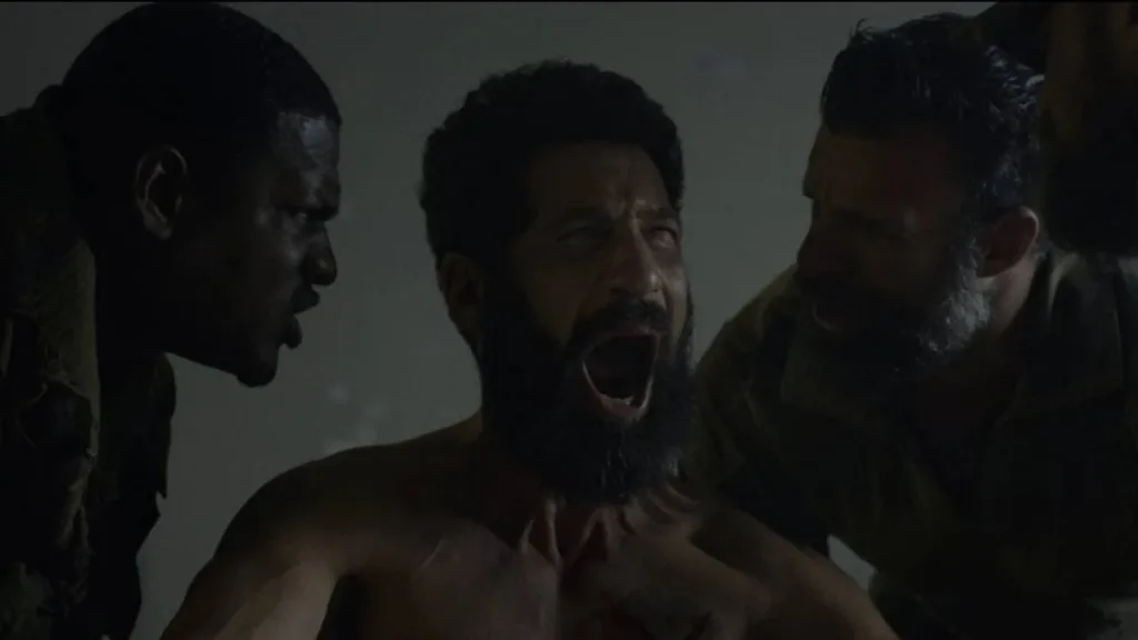 O Justiceiro: Uma Última Morte | Justiceiro Retorna ao Caos e aos Próprios Fantasmas em Especial 1 Jon Bernthal como Frank Castle em "Justiceiro: Uma Última Morte". Cercado de homens, seminu o protagonista grita desesperado em sala escura.