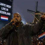 Kanye West de noite durante chuva em apresentação na Holanda, onde sua vinda havia sido suspensa. Imagem gerada por IA.