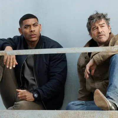 Aaron Pierre (esquerda) e Kyle Chandler (direita) como dois lanternas na nova série adaptada dos quadrinhos da DC sobre os heróis, interpretando John Stewart e Hal Jordan, respectivamente. Ambos estão sentados olhando distante.