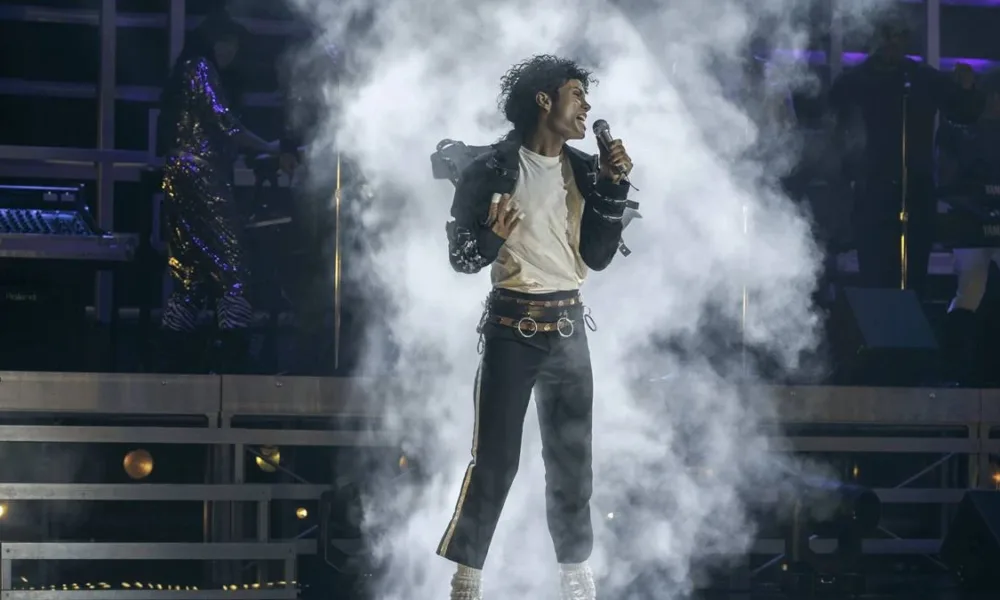 Jaafar Jackson na cinebiografia "Michael", interpretando o tio Michael Jackson. Ele está no palco cheio de gelo seco ao fundo em performance.