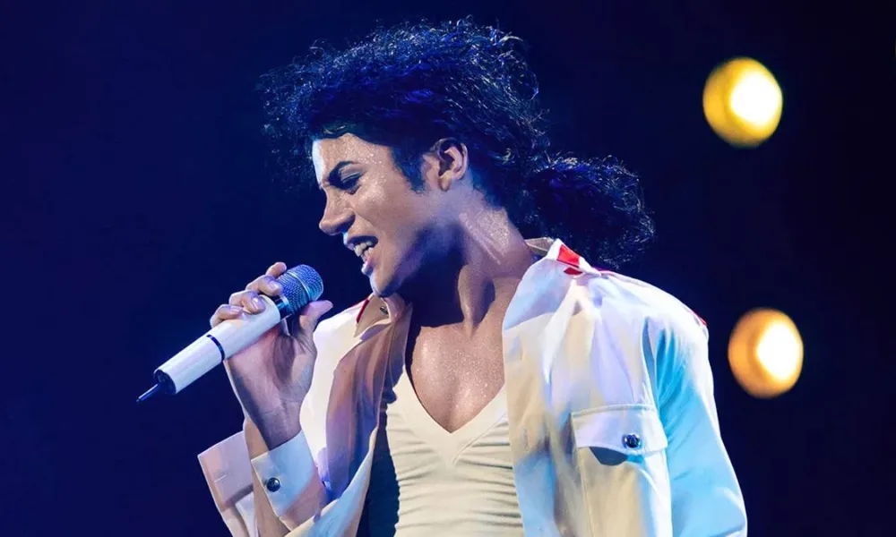 Jaafar Jackson caracterizado como seu tio, Michael Jackson, no filme biográfico "Michael" em performance com trajes brancos.