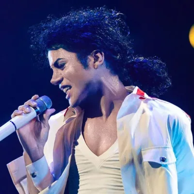 Jaafar Jackson caracterizado como seu tio, Michael Jackson, no filme biográfico "Michael" em performance com trajes brancos.