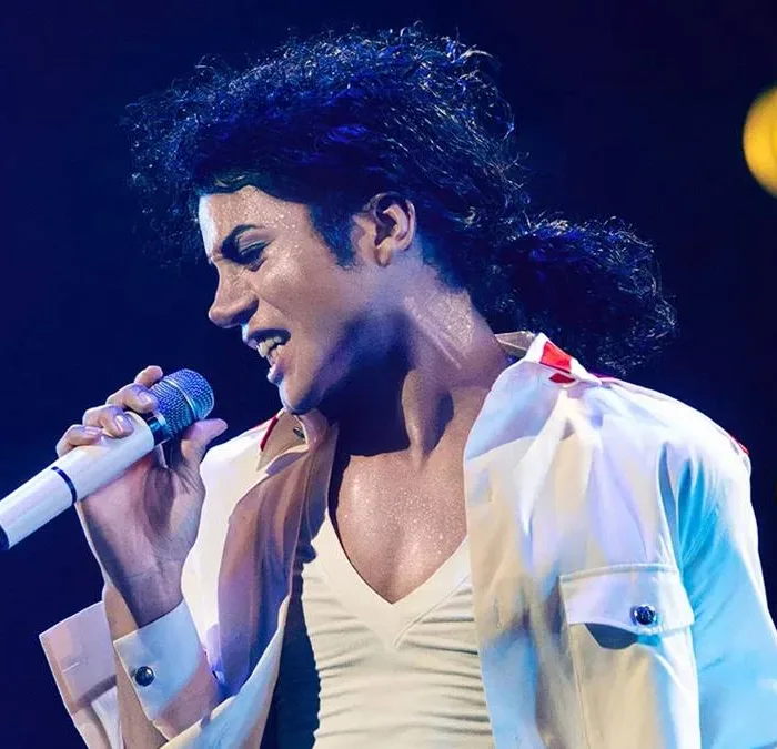 Jaafar Jackson caracterizado como seu tio, Michael Jackson, no filme biográfico "Michael" em performance com trajes brancos.