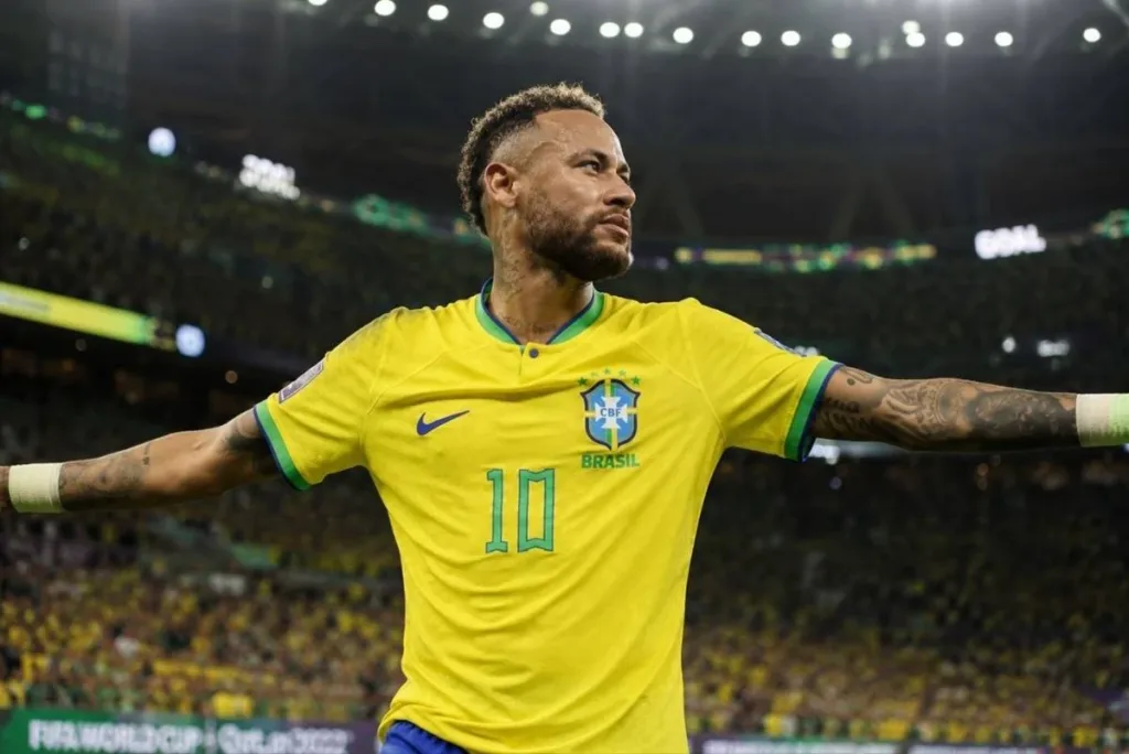 Neymar é Convocado por Ancelotti e Disputará Sua Quarta Copa do Mundo Pela Seleção Brasileira 1 Neymar em partida com a camisa da seleção brasileira. Braços abertos, corrida leve, expressão neutra. Imagem gerada por IA.