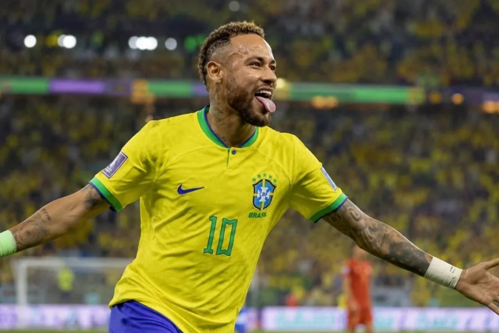 Neymar é Convocado por Ancelotti e Disputará Sua Quarta Copa do Mundo Pela Seleção Brasileira 2 Neymar em partida com a camisa da seleção brasileira. Braços abertos, corrida média, língua pra fora em sorriso. Imagem gerada por IA.