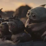 Grogu cercado de outros alienígenas em "O Mandaloriano e Grogu" em um fundo de fim de tarde numa paisagem desértica do filme "Mandaloriano e Grogu".
