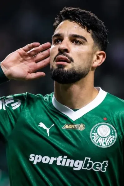 Esta imagem mostra o atacante argentino José Manuel "Flaco" López, que atualmente joga pelo Palmeiras. Ele leva a mão esquerda à orelha. Imagem gerada por IA.