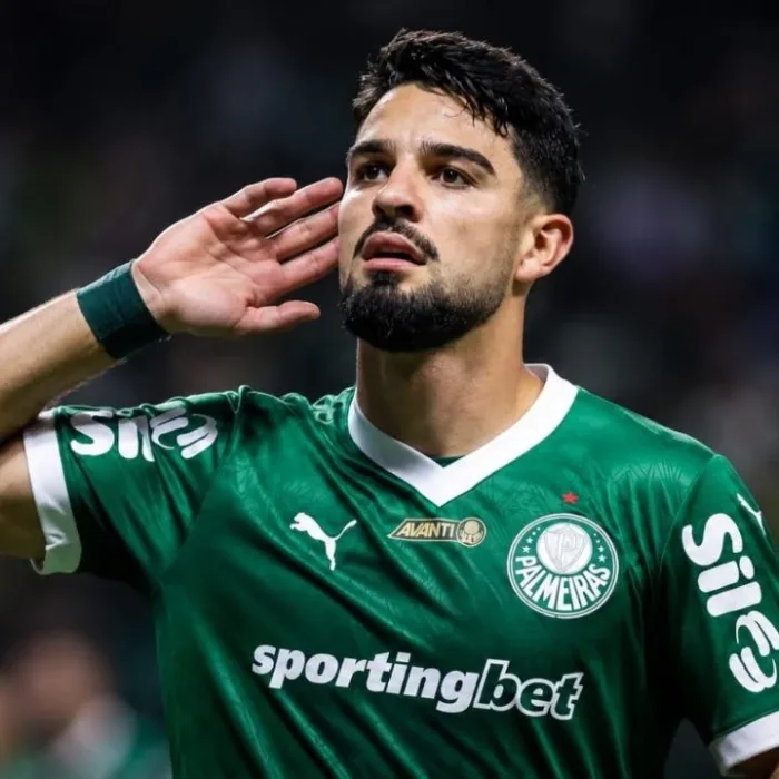 Esta imagem mostra o atacante argentino José Manuel "Flaco" López, que atualmente joga pelo Palmeiras. Ele leva a mão esquerda à orelha. Imagem gerada por IA.