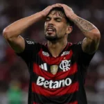 Esta imagem mostra Lucas Paquetá vestindo a camisa do Flamengo. Ele leva as mãos à cabeça em desespero. Imagem gerada por IA.