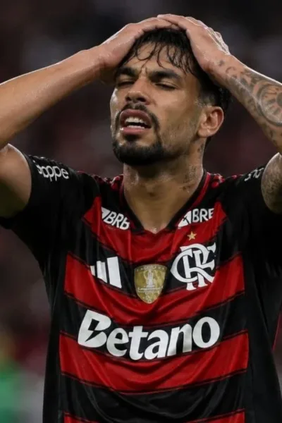 Esta imagem mostra Lucas Paquetá vestindo a camisa do Flamengo. Ele leva as mãos à cabeça em desespero. Imagem gerada por IA.