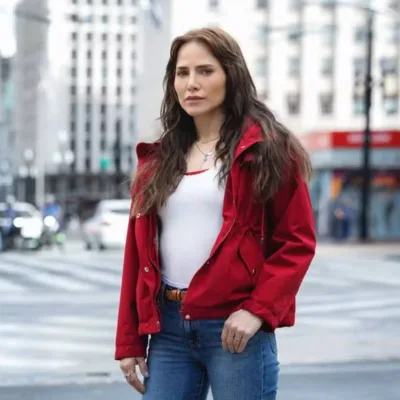 Letícia Collin como personagem protagonista da nova novela das 9, "Quem Ama Cuida". Ela está de jaqueta vermelha e uma paisagem urbana de São Paulo ao fundo.