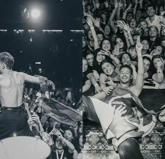 Colagem com duas fotos postadas pelo cantor italiano Ruggero de show seu em São Paulo dia 29 de maio de 2026. Na primeira sem camisa, de costas, na segunda deitado no palco, coberto com uma bandeira do Brasil, sorrindo e posando com a plateia ao lado do guitarrista, posando para foto. Foto em PB.