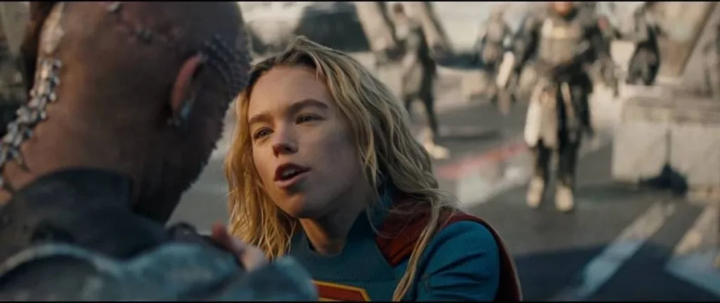 Supergirl Revela Novas Imagens Inéditas e Destaca Visual da Heroína em Meio ao Caos de Uma Guerra Galáctica 1 Nova imagem de "Supergirl", filme de 2016. Protagonista em ambientação de guerra põe mãos nos ombros de alguém, visto de costas.