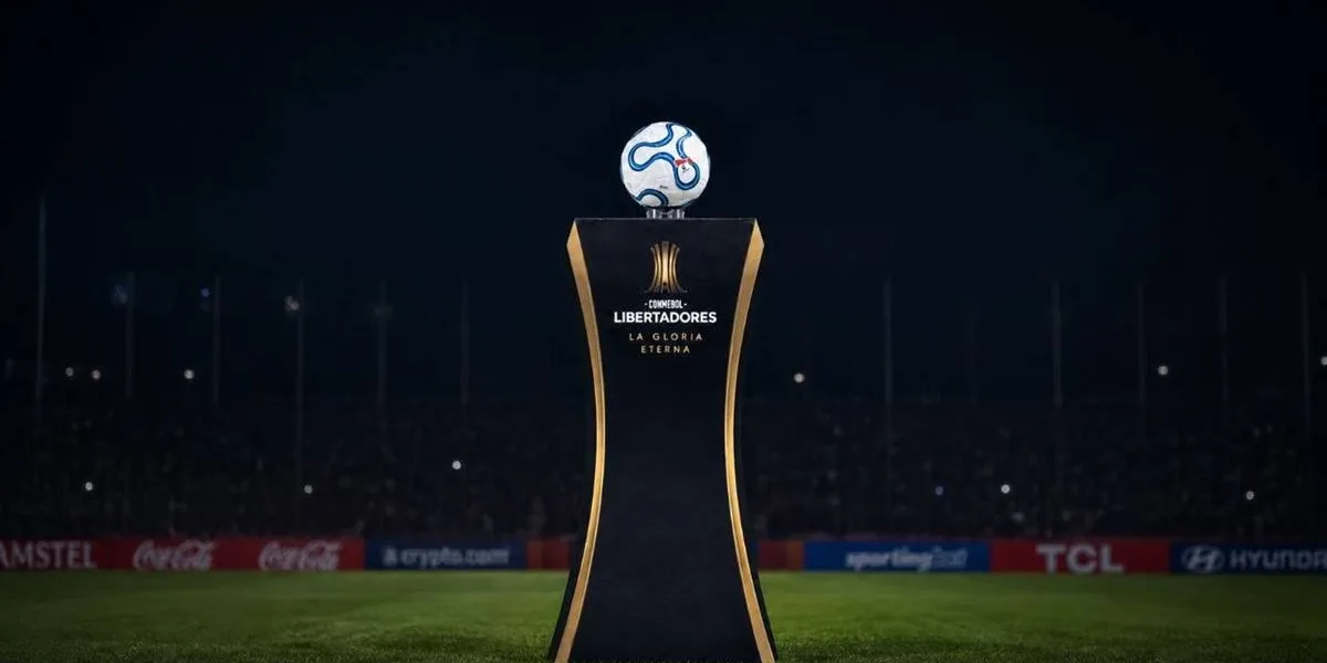 Troféu da Copa Libertadores sobre estande sobre o gramado de noite. Imagem gerada por IA.