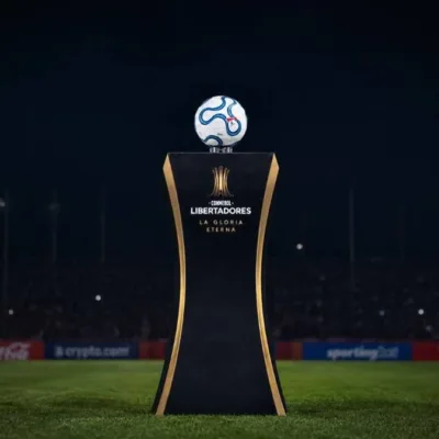 Troféu da Copa Libertadores sobre estande sobre o gramado de noite. Imagem gerada por IA.