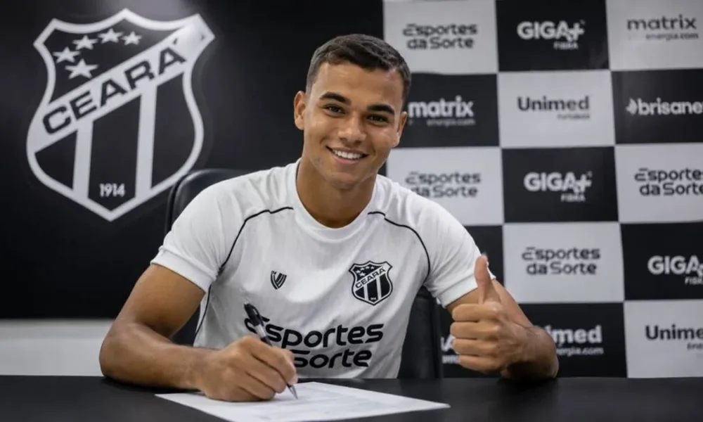 Vinicius Uchella, 20, assinando contrato com o Ceará Sporting Club, com a camisa do time e uma parede de coletiva de imprensa ao fundo. Imagem gerada por IA.