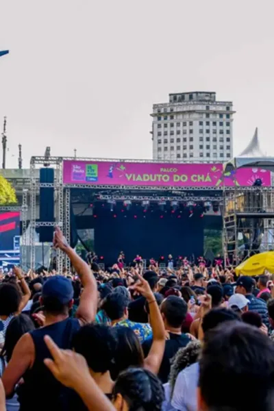 Vista do público de palco do Viaduto do Chá durante virada cultural de São Paulo. Está de dia e show está cheio.