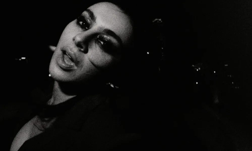 Esta imagem mostra a cantora Charli XCX em um registro em preto e branco para o clipe de sua música "Rock Music".
