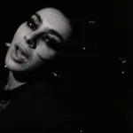 Esta imagem mostra a cantora Charli XCX em um registro em preto e branco para o clipe de sua música "Rock Music".