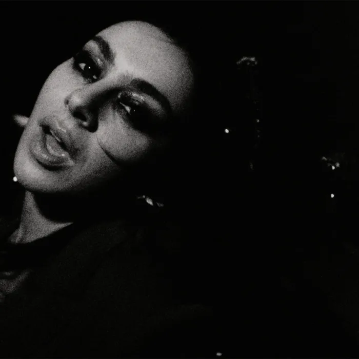 Esta imagem mostra a cantora Charli XCX em um registro em preto e branco para o clipe de sua música "Rock Music".
