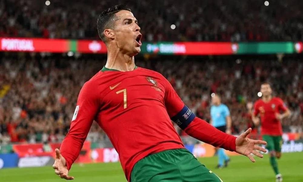 Cristiano Ronaldo comemora gol dando carrinho, camisa da seleção portuguesa. Imagem gerada por IA.