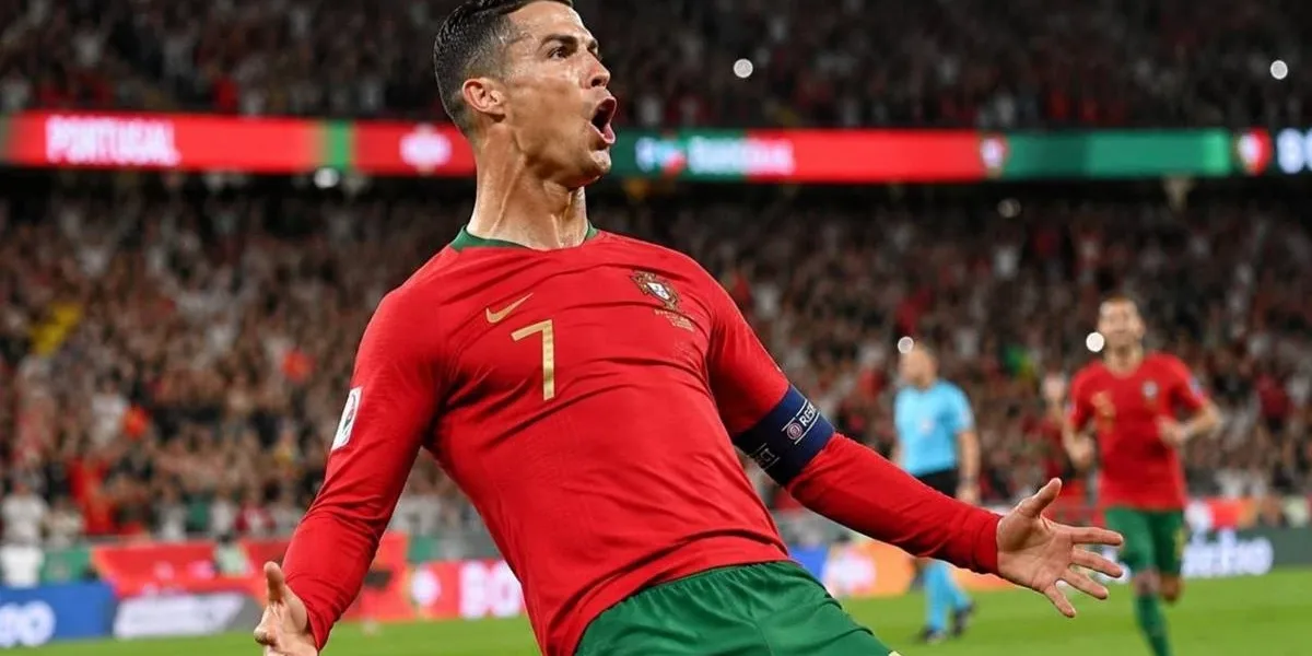 Cristiano Ronaldo comemora gol dando carrinho, camisa da seleção portuguesa. Imagem gerada por IA.