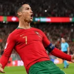 Cristiano Ronaldo comemora gol dando carrinho, camisa da seleção portuguesa. Imagem gerada por IA.