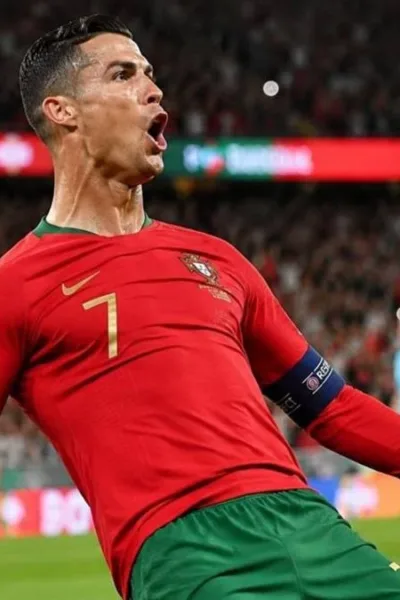 Cristiano Ronaldo comemora gol dando carrinho, camisa da seleção portuguesa. Imagem gerada por IA.