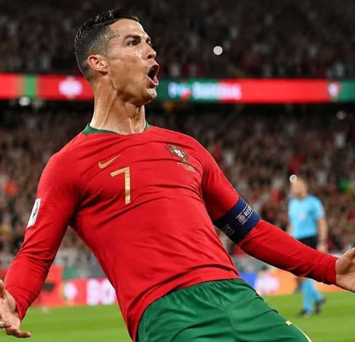 Cristiano Ronaldo comemora gol dando carrinho, camisa da seleção portuguesa. Imagem gerada por IA.