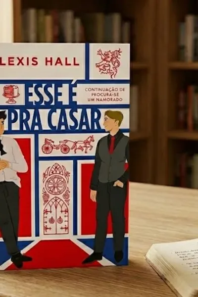 O livro na imagem é "Esse é pra casar", de Alexis Hall, de pé em um ambiente confortável de leitura, com uma estante ao fundo, luz ambiente diurna. Há um livro com anotações e caneta, e um óculos fechado na mesma mesa.