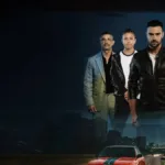 Esta imagem é o pôster do filme de ação romeno "The Race" (também conhecido como "Cursa"), lançado em 2025. Imagem de carros em corrida em estrada com silhueta dos personagens posando acima.