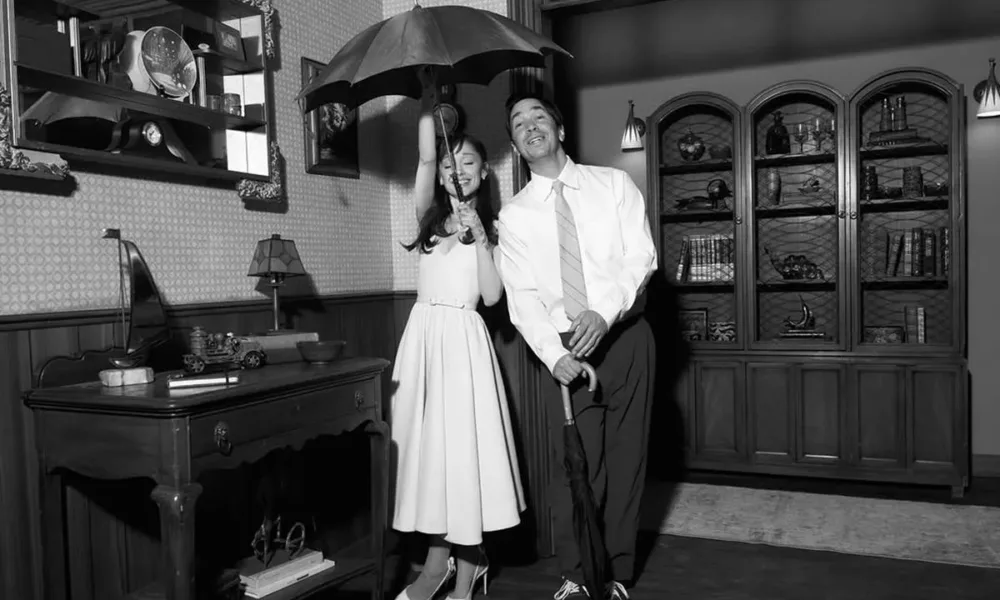 Ariana Grande e Justin Long em foto debaixo de guarda chuva em ambiente interno, temática dos anos 50, preto e branco, para o clipe de "Hate That I Made You Love Me".