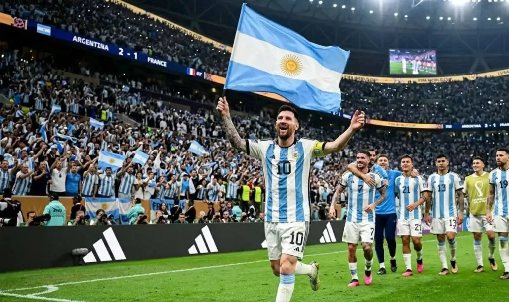 Messi carrega bandeira da Argentina com camisa da seleção em campo ao lado de outros jogadores da seleção argentina. Imagem gerada por IA.