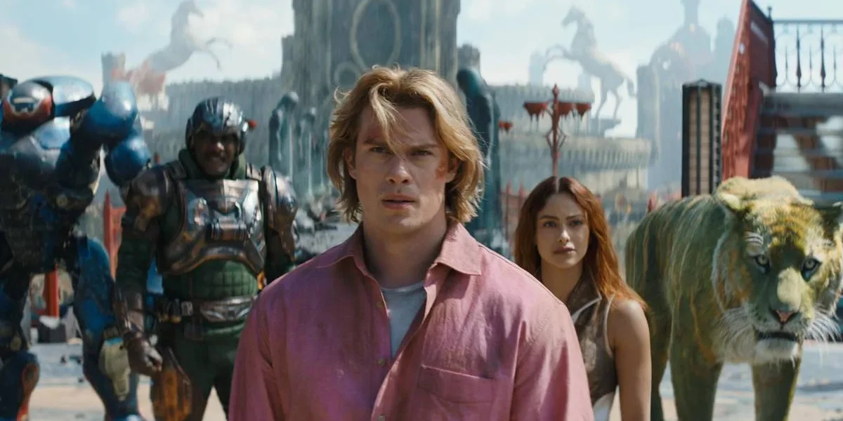 Mestres do Universo | Filme Entrega Exatamente o que Precisava e Abre Caminho Para um Universo Muito Maior Esta é uma cena do filme live-action Mestres do Universo, com estreia prevista para junho de 2026. Adam está ao centro, camisa rosa, e o elenco de Eternia ao fundo.